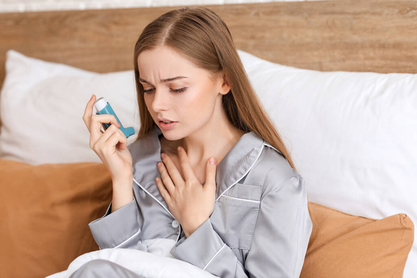 Sick young woman with inhaler in bed - Foto, Imagen
