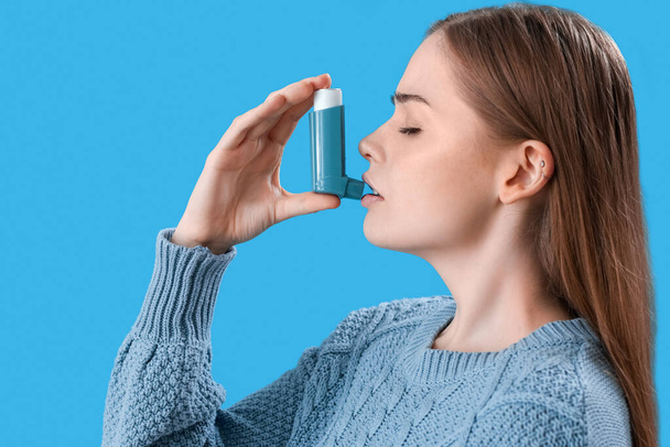 Sick young woman with inhaler on blue background - Fotoğraf, Görsel