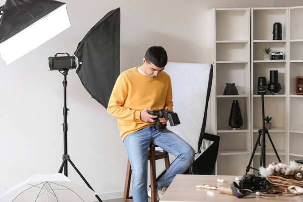 Fiatal férfi fotós professzionális kamera dolgozik stúdióban - Fotó, kép