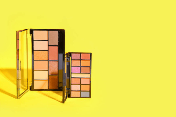 Palettes of eyeshadows on yellow background - Foto, afbeelding