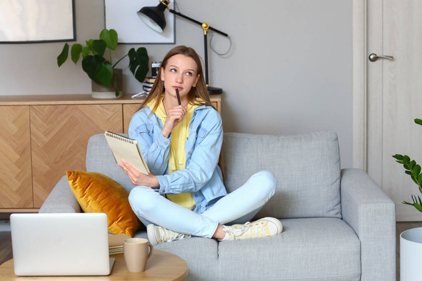 Adolescente réfléchie avec ordinateur portable à la maison - Photo, image