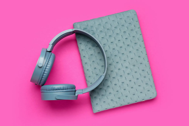 Modern blue headphones with notebook on pink background - Photo, Image