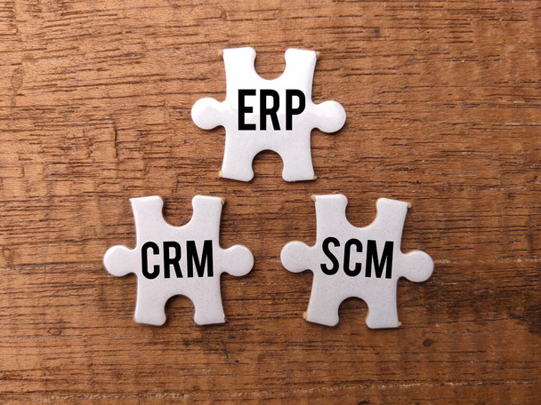 Top view witte puzzel met het woord ERP CRM SCM op een houten achtergrond. - Foto, afbeelding