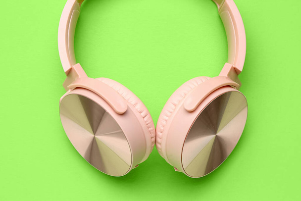 緑の背景に現代のピンクのヘッドフォン - 写真・画像
