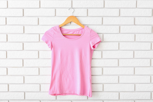 Pink t-shirt hanging on white brick wall - Foto, Bild