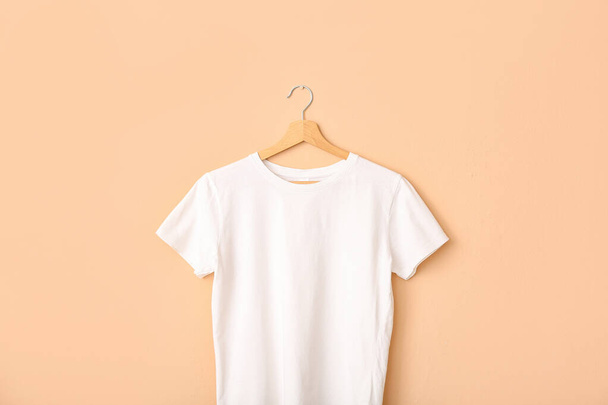White t-shirt hanging on light wall - Foto, imagen