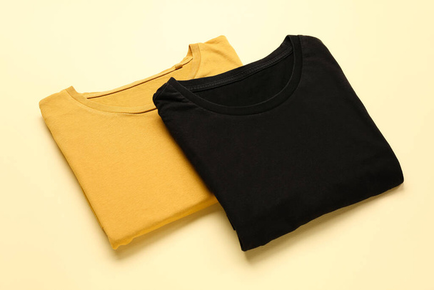 Folded yellow and black t-shirts on color background - Foto, afbeelding