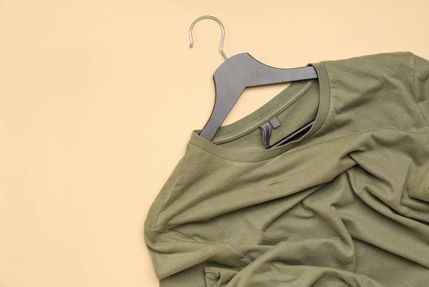 Crumpled green t-shirt with hanger on beige background - Foto, Imagem
