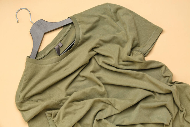 Crumpled green t-shirt with hanger on beige background - Zdjęcie, obraz