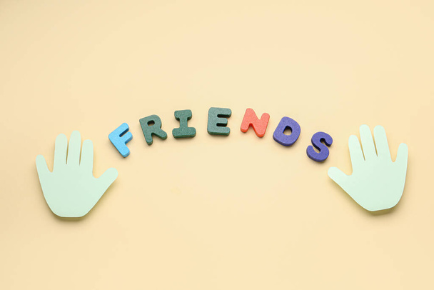Paper palms and word FRIENDS on beige background. Friendship Day celebration - Photo, Image