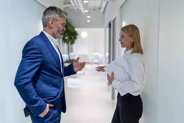 Side view of an elegant female entrepreneur talking to her business partner in the office corridor - Valokuva, kuva