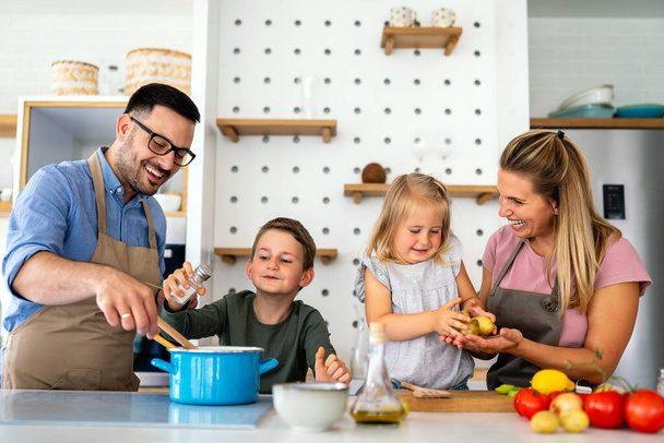 Happy young family preparing healthy food together in kitchen. People happiness cooking concept - Photo, image
