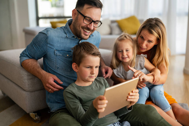 Happy young family having fun time at home. Parents with children using digital device. Education parenting happinness concept. - Foto, imagen