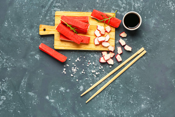 Wooden board with tasty crab sticks and sauce on green background - Photo, Image
