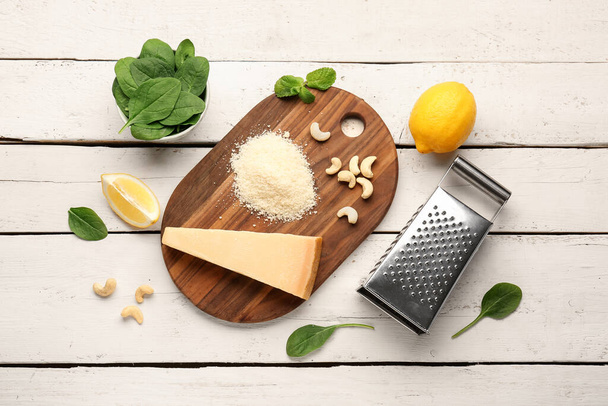 Board with tasty Parmesan cheese and grater on light wooden background - Fotó, kép