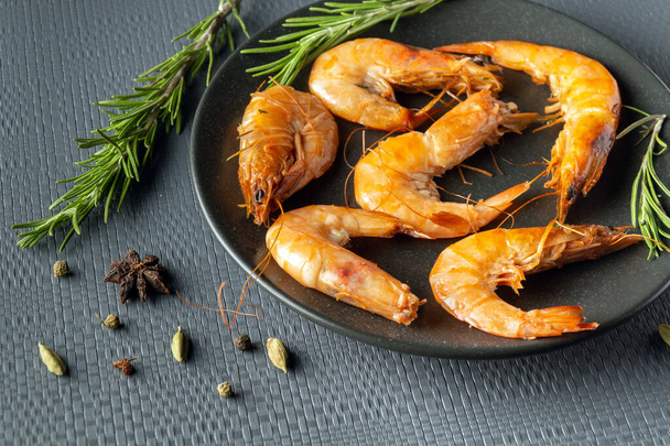 Shrimps or prawns with rosemary in a bowl on a gray table. The idea of dietary seafood for lunch or dinner. - Photo, Image