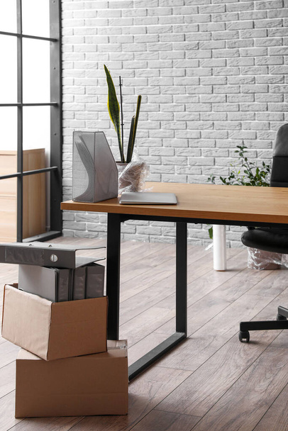 Рабочее место с картонными коробками в офисе в день переезда - Фото, изображение