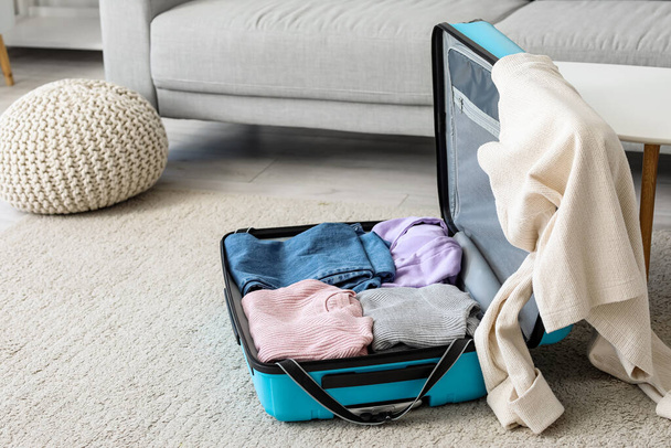 Open suitcase with clothes in living room - Foto, afbeelding