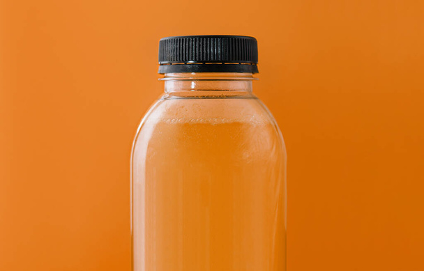 黄色の背景に新鮮なオレンジジュースのボトル - 写真・画像