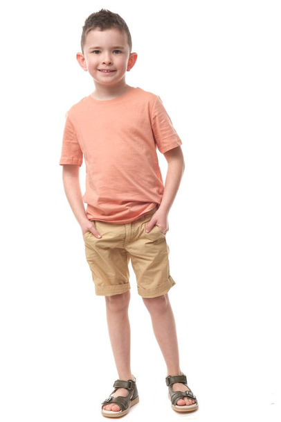 Attractive young boy in pastel t-shirt and shorts on isolated white background. - Фото, изображение
