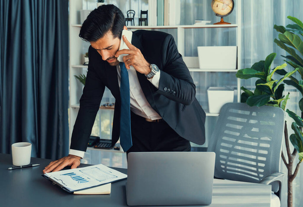 Szorgalmas üzletember elfoglalt beszél a telefonon az ügyfelekkel, miközben dolgozik laptop irodájában, mint a koncepció a modern keményen dolgozó irodai dolgozó életmód mobiltelefonnal. Fertőzött - Fotó, kép