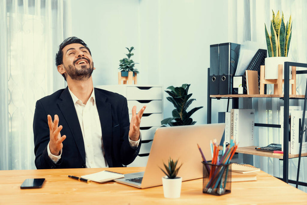 Homme d'affaires excité et heureux habillé en costume formel noir, levez le bras en geste de célébration à son bureau, après avoir réussi la promotion de l'emploi, l'énergie et la joie en tant que gagnant d'entreprise. Fervent - Photo, image