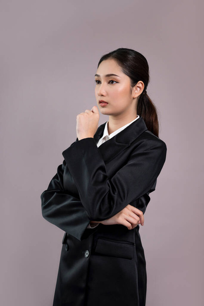 Confident young businesswoman stands on isolated background, posing in formal black suit. Office lady or manager with smart and professional appearance. Enthusiastic - Фото, зображення
