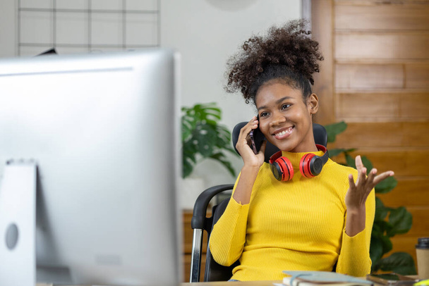 Młoda Amerykanka to początkująca bizneswoman, siedzi w swoim biurze i rozmawia przez telefon ze swoim partnerem, kierownictwem i biznesem z nowego pokolenia. Koncepcja zarządzania przedsiębiorstwem typu start-up. - Zdjęcie, obraz