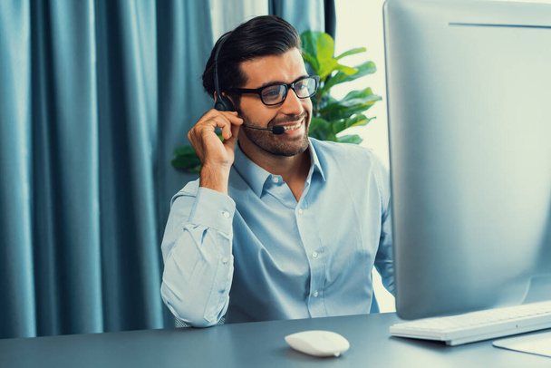 Muž operátor call centra nebo telesales zástupce sedí u svého psacího stolu nosí sluchátka a zabývá se rozhovorem s klientem poskytující zákaznickou podporu nebo prodej. horlivý - Fotografie, Obrázek