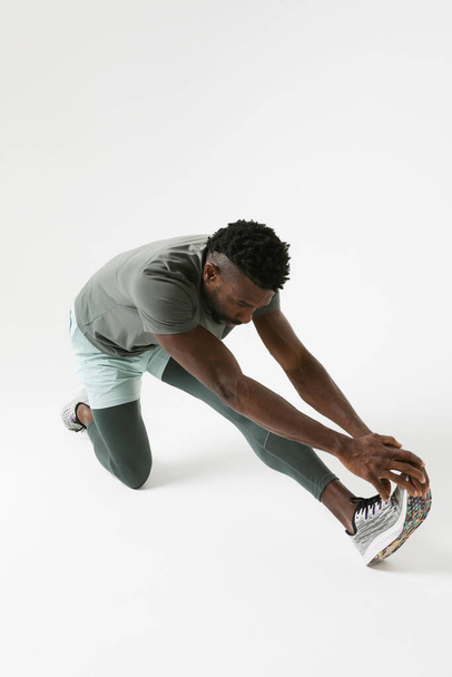 Vertical photo of athletic man doing muscle stretching exercises. Mock-up. High quality photo. - 写真・画像