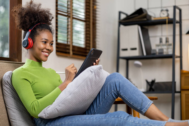 An American teenage woman is in the living room, she is spending her weekends at home playing social media and watching movies. The concept of living on vacation. - Photo, Image
