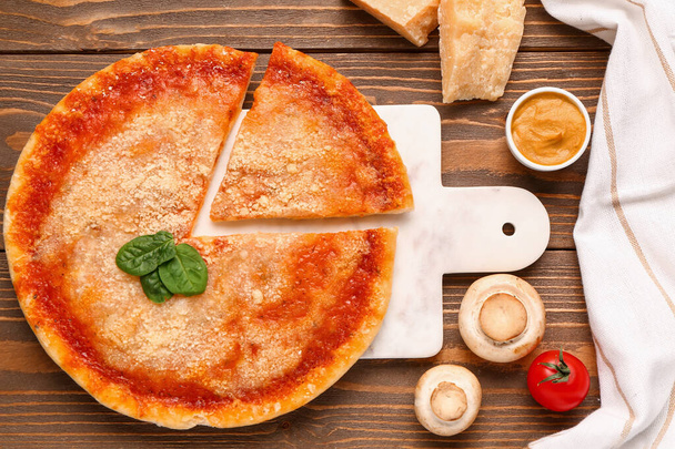 Planche de pizza savoureuse au parmesan, basilic et sauce sur fond de bois - Photo, image