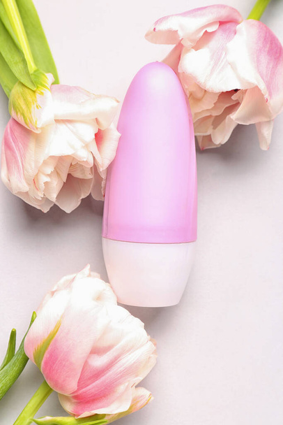 Бутылка дезодоранта и цветы на белом фоне - Фото, изображение