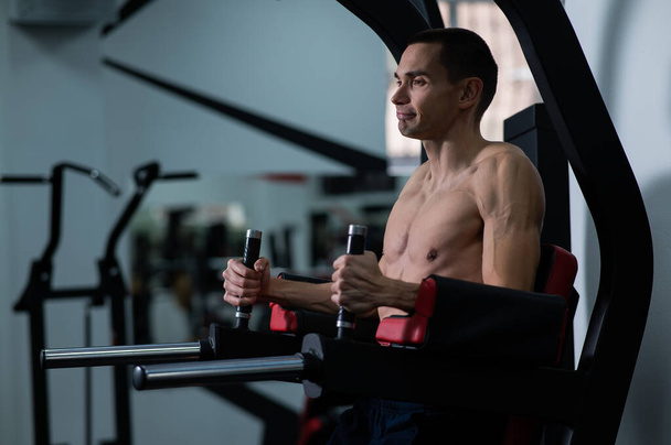 Shirtless man doing triceps dips from parallel bars in gym - Foto, Imagem