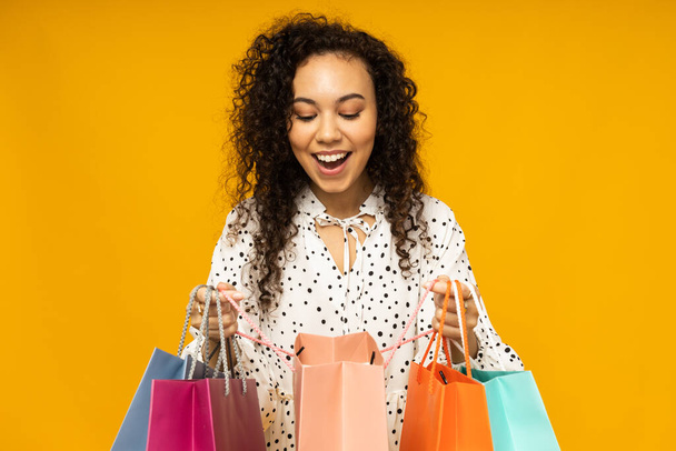 Young woman with shop bags on yellow background - Photo, Image