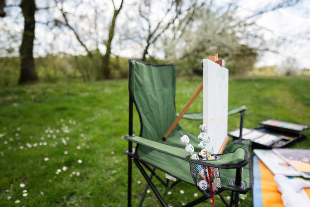 Drawing set on chair outdoor on picnic blanket painting at garden spring park, relaxation. - Fotó, kép