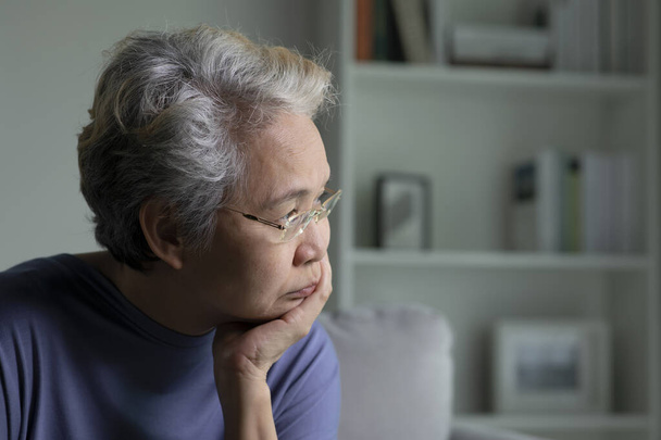 Ritratto di donna anziana asiatica triste e sola in salotto - Foto, immagini