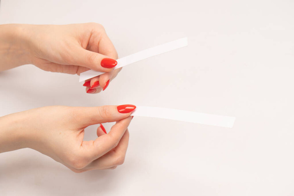 Woman hand with red nails with test strips for the perfume, isolated on a white background. Perfume blotters. - Foto, Imagen