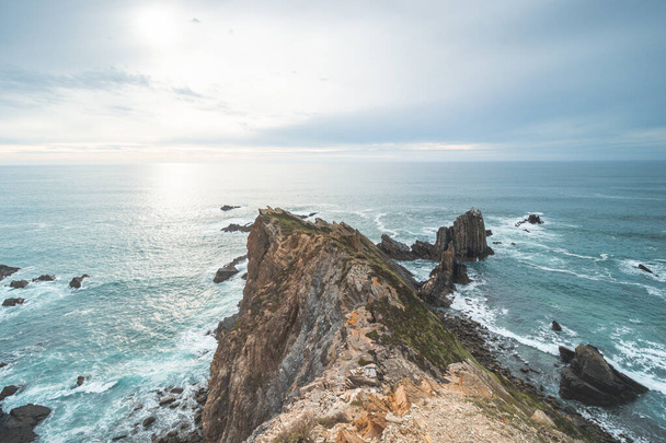 Rugged rock and cliff coastline on the Atlantic Ocean near the town of Odeceixe in the west of Portugal in the famous tourist region of the Algarve. Sunset. - Фото, зображення