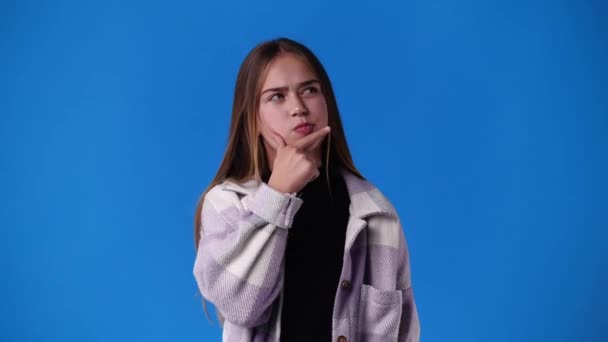 4k Video von einem Mädchen, das für ein Video auf blauem Hintergrund posiert. Konzept der Emotionen. - Filmmaterial, Video