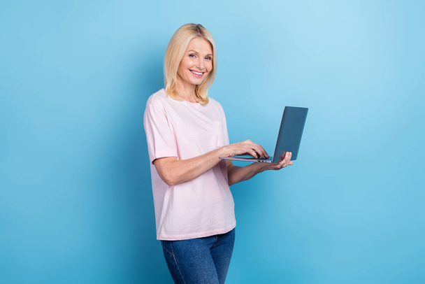 Photo of positive aged person hold use wireless netbook write email isolated on blue color background. - Fotoğraf, Görsel