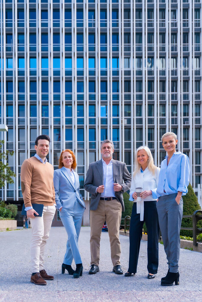 Portrait of cheerful group of coworkers walking outdoors in a corporate office area laughing - Foto, Bild