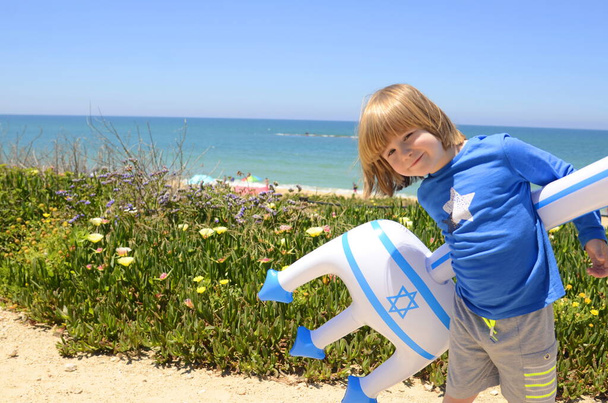 Un petit garçon avec un jouet gonflable avec le drapeau d'Israël et l'étoile de David. Concept : stations balnéaires israéliennes, plages, mer. Jour de l'indépendance d'Israël, patriotisme. - Photo, image