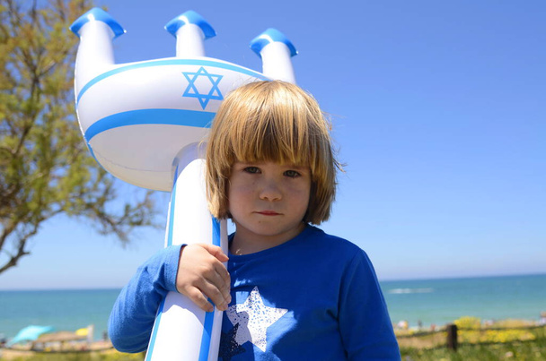 Um menino pequeno com um brinquedo inflável com a bandeira de Israel e a estrela de David. Conceito: resorts israelenses, praias, mar. Dia da independência de Israel, patriotismo. - Foto, Imagem
