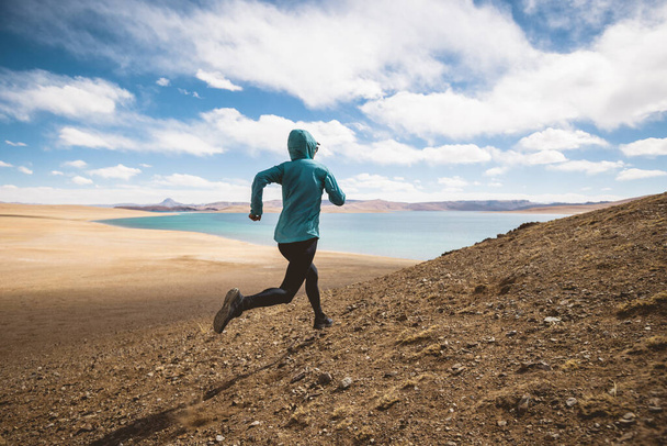 Woman trail runner cross country running in lakeside mountains - Fotó, kép