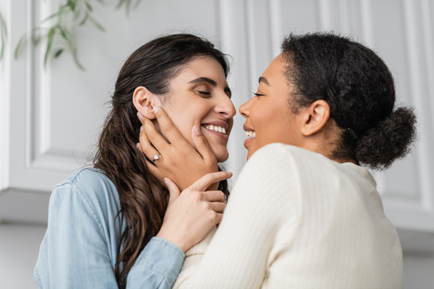 overjoyed multiracial woman with engagement ring on finger hugging with smiling girlfriend  - Foto, Imagem