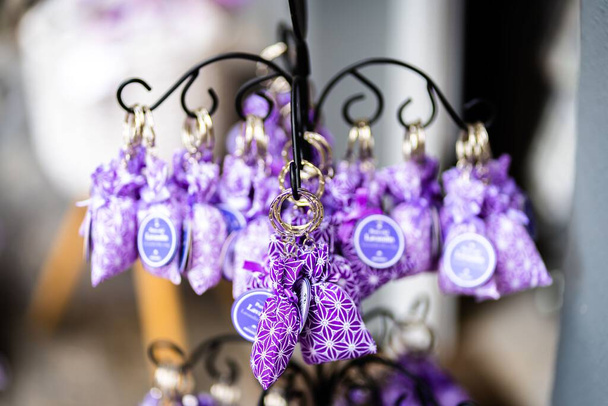 A selective focus of purple key chain hanging on a metal stand at souvenir shop - Foto, Bild