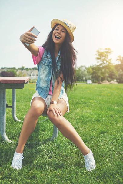 Ti mando tanto amore. una giovane donna attraente che si fa dei selfie mentre trascorre una giornata nel parco - Foto, immagini