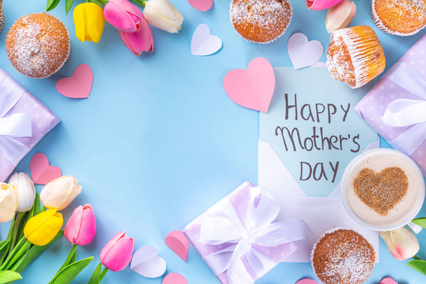 Äitienpäivän loma-onnittelukortti. Äitienpäivä aamu aamiainen söpö yllätys tausta, lahja laatikot, cupcakes, kahvi muki, sydän sisustus, tulppaanit ja kukat, Hyvää äitienpäivää kirje - Valokuva, kuva