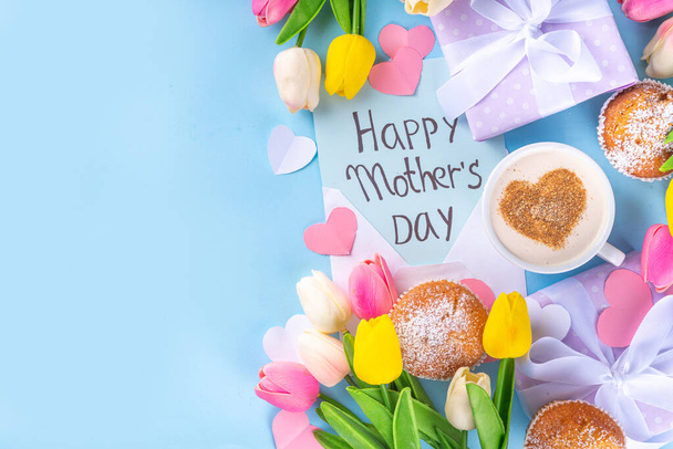 Pozdrav na Den matek. Den matek ranní snídaně s roztomilým překvapením pozadí, s dárkovými krabicemi, cupcakes, hrnek na kávu, srdce dekor, tulipány a květiny, Happy Mother 's Day letter - Fotografie, Obrázek